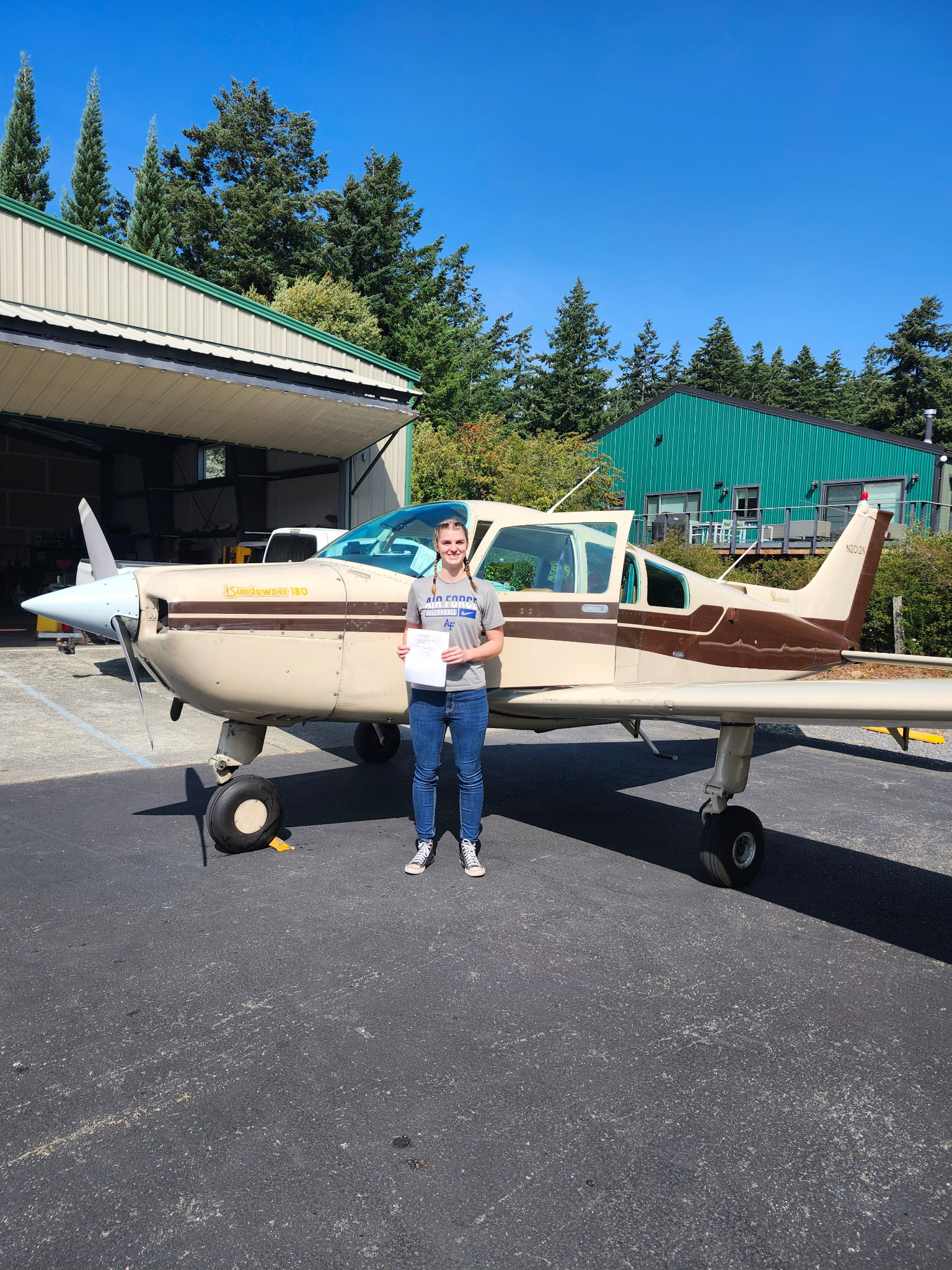 A youth scholarship recipient holding her certificate beside the club Sundowner at Orcas Island